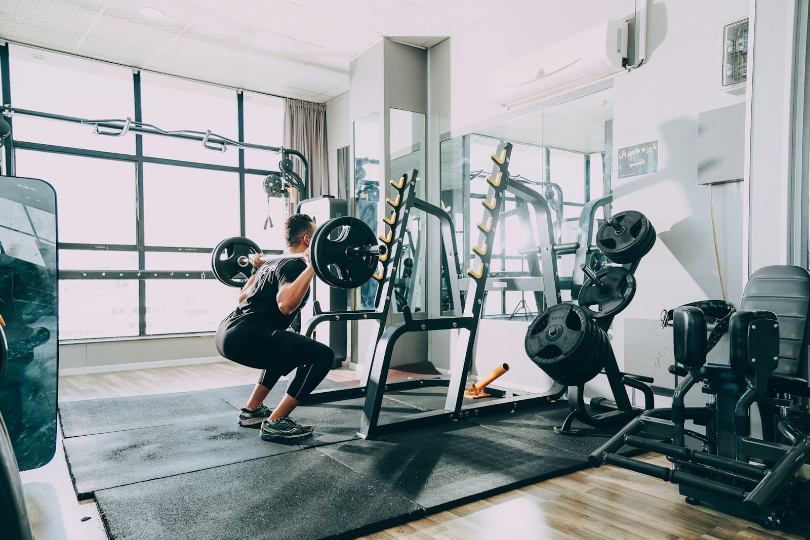 Person squatting in a bright, quiet gym